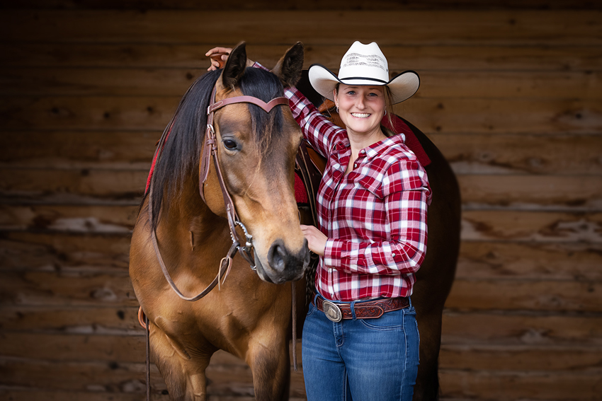 Cowboylady vor schwarzem Hintergund mit Pferd