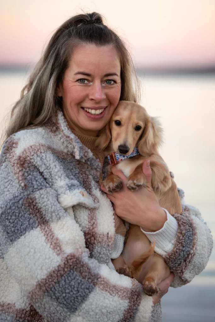 Frau hält Hund am Strand