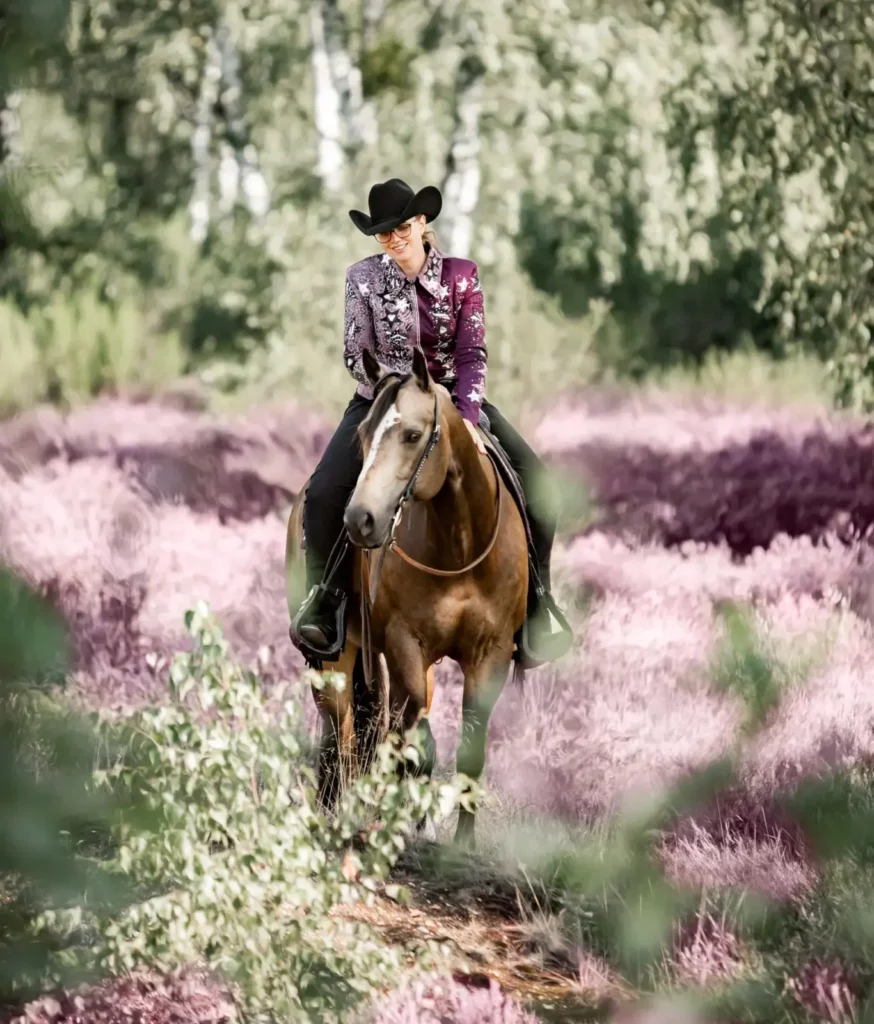 Reiterin auf Pferd in blumiger Landschaft